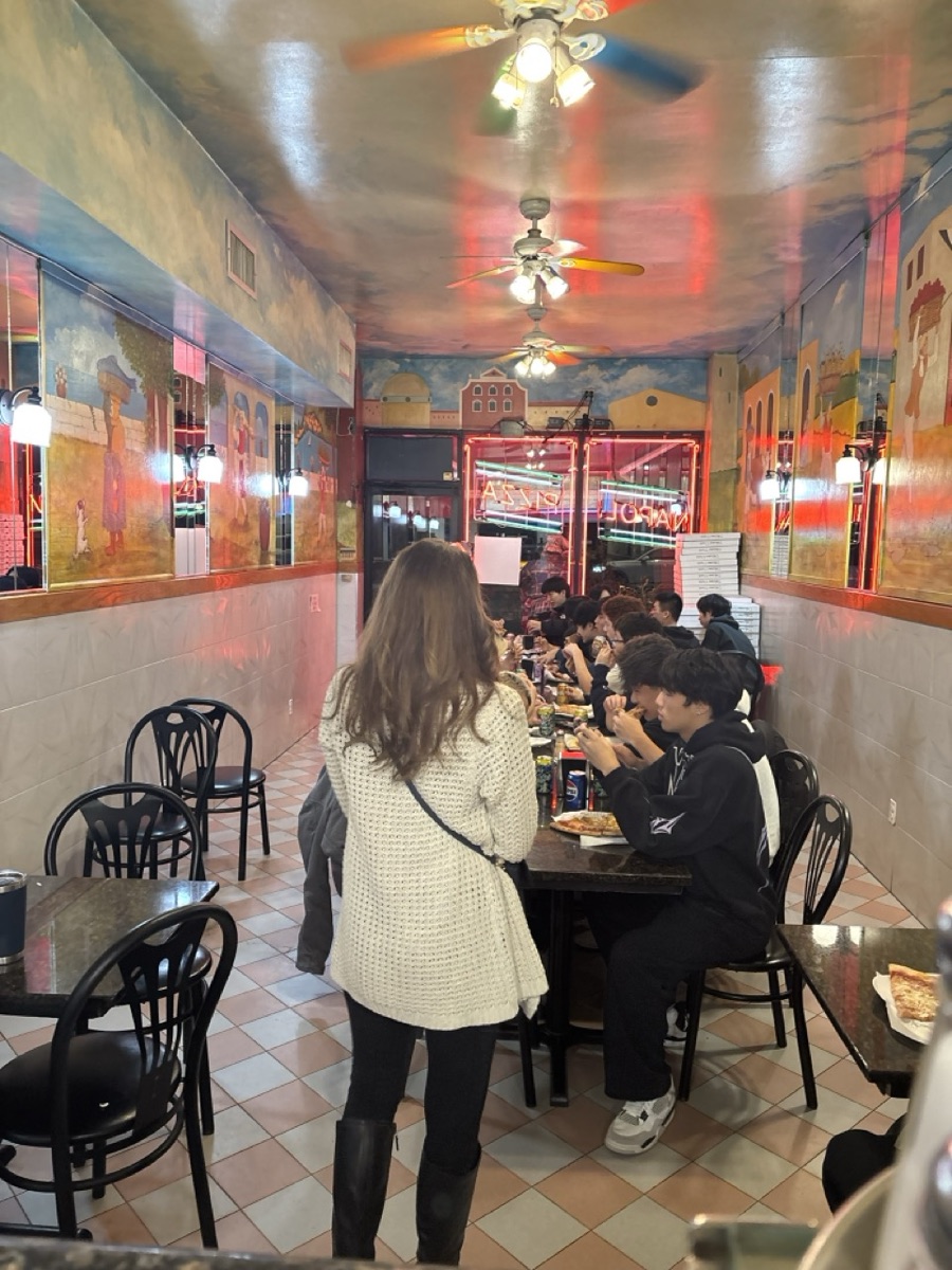 A group sharing pizza at a long table beneath the murals and painted sky ceiling at Napoli Pizza