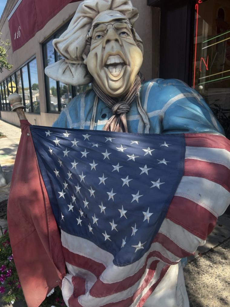 The hand-carved chef who stands outside Napoli Pizza on Northern Boulevard, holding an American flag