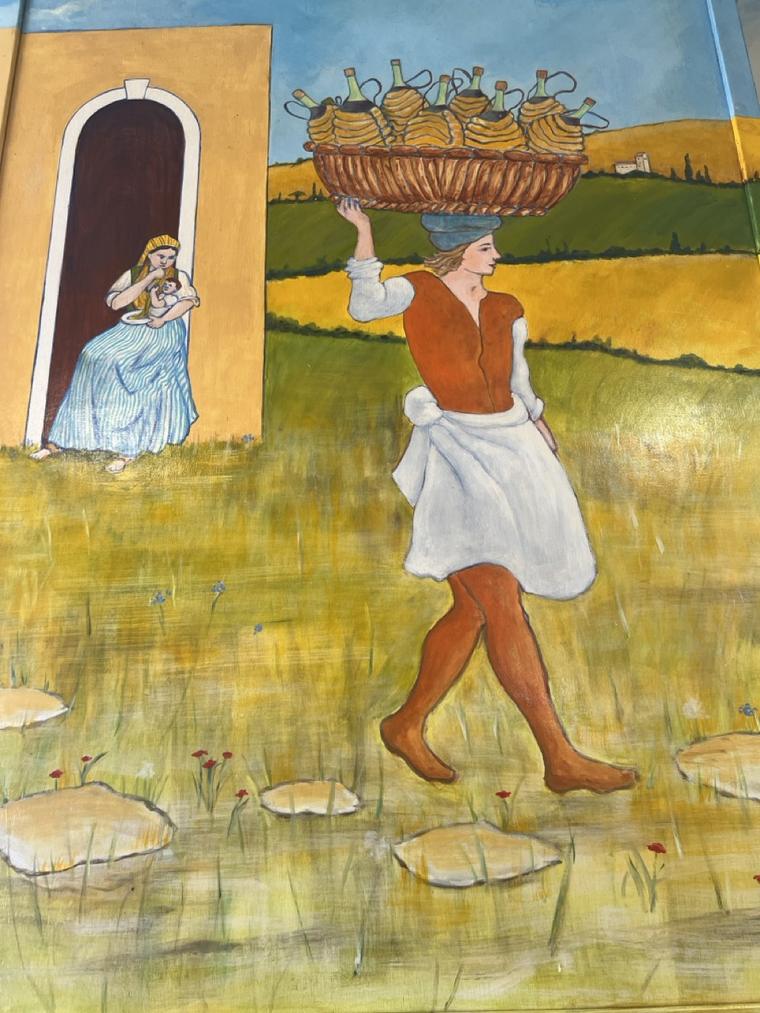 Hand-painted mural of a villager carrying a basket of straw-wrapped wine bottles through golden fields