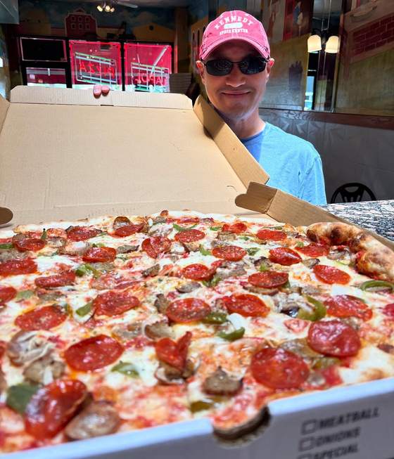 A customer with a full pepperoni and sausage pie in the box