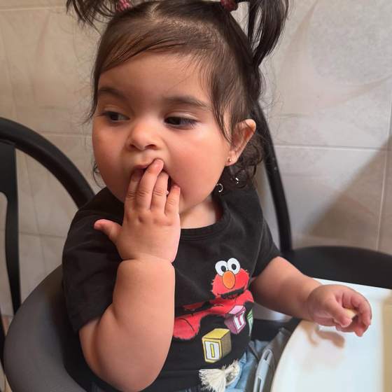 A toddler in a high chair having a snack